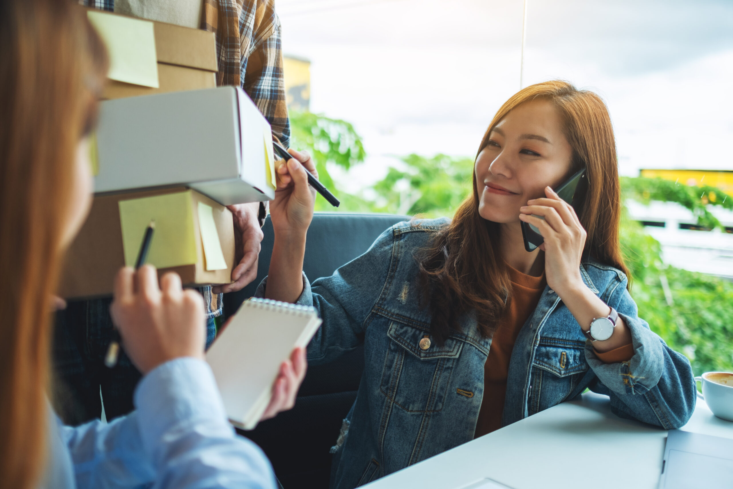 A group of young entrepreneur confirming and checking orders from customer on the phone for online shopping and delivery concept